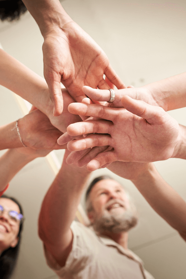 Mãos de pessoas unidas em sinal de confiança e integridade no trabalho em equipe, representando valores da GrowPath