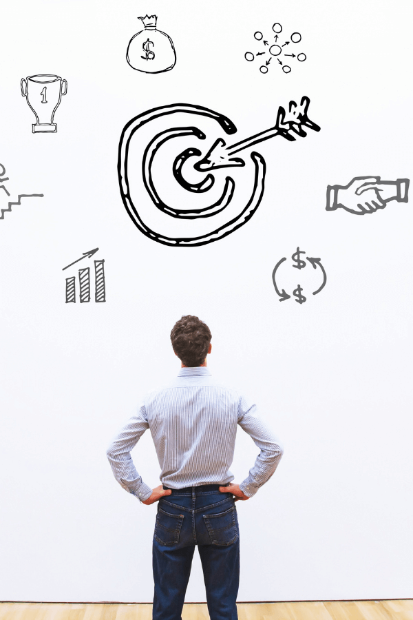 Empresário olhando para desenho de alvo e ícones de crescimento financeiro e metas estratégicas, simbolizando objetivos claros para empresas com a GrowPath